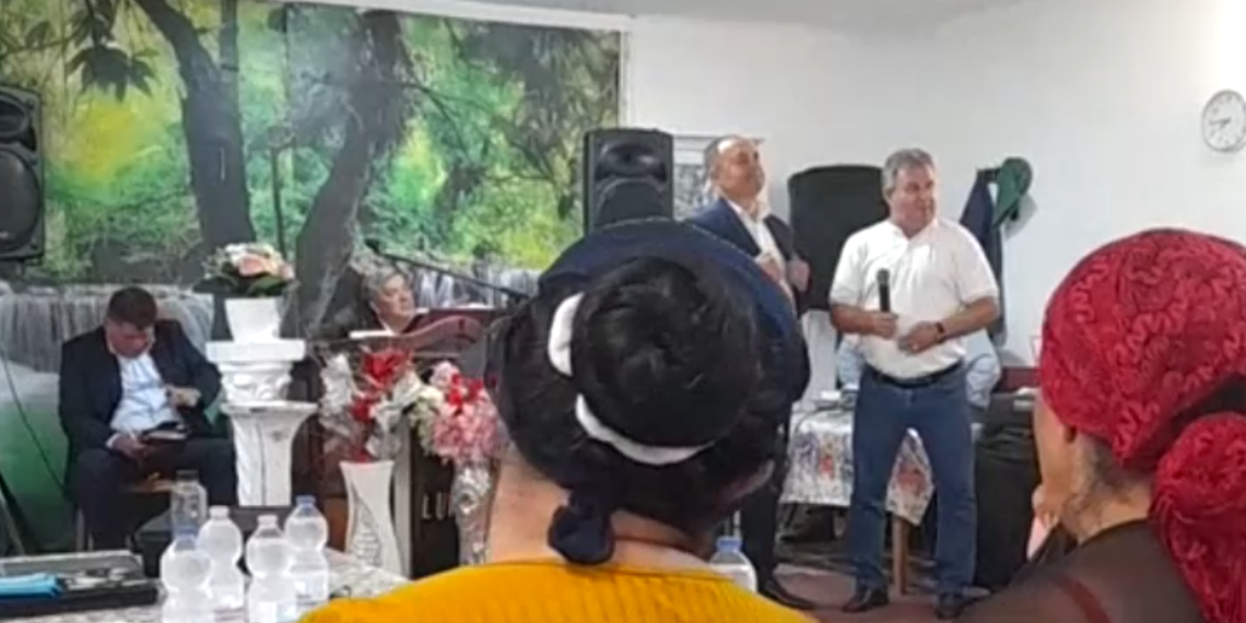 VIDEO. Înregistrări halucinante cu primarul de Ineu în campanie la biserica din colonia de rromi. Spune că Morna, contracandidatul său va trimite milițienii să-i băge în lagăre. „Eu trec pe lângă voi, nu vă ascult, îmi rupeți un picior, nu-i bai…Ne și înjurăm, ne și certăm, dar ne împăcăm.. M-au sunat românii din Botean: Știți ce zic români: domn primar, o zis că sunteți cu țâganii…Nu mi-e rușine, eu știu limba țâgănească, o și vorbesc pretutindeni…Vin să vă cumpere pe un kil de ulei…Ori te duci cu ăla ca mine și care nu-i nici 100% la cap si vă oferă ajutor la orice oră, ori cu ăla care vine cu dronele” 